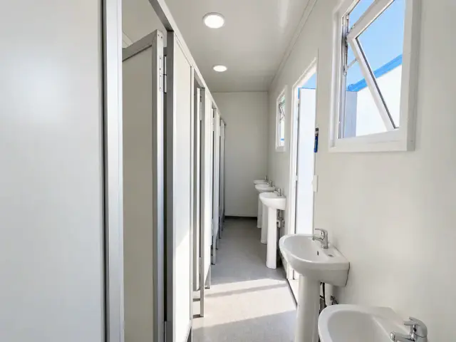 Pasillo interior con los lavamanos en fila y las cabinas de WC enfrentadas