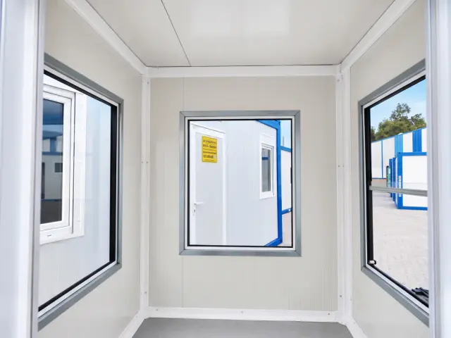 El interior desde la puerta: la vuelta completa de ventanales, con el depósito al otro lado del vidrio