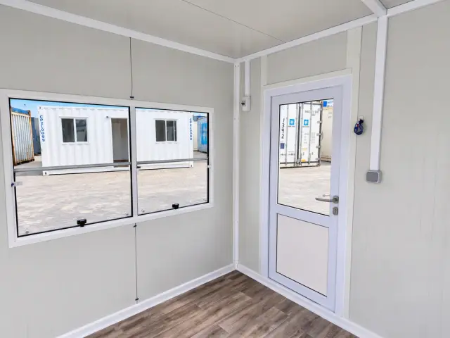 El interior mirando hacia la puerta, con el ventanal a la izquierda y el pulsador junto al marco