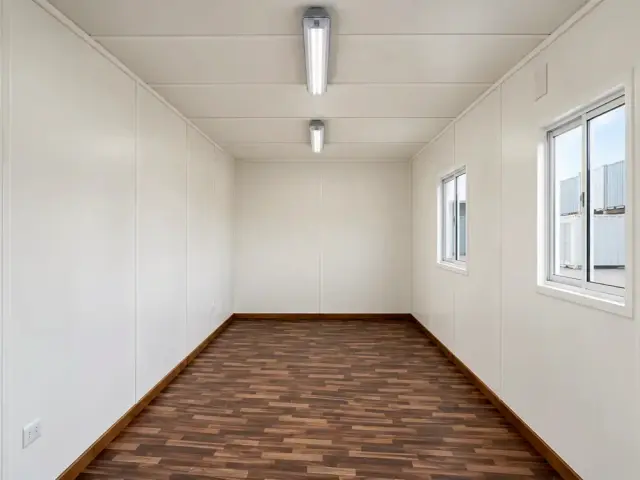 Interior forrado del 40 pies visto desde el fondo, con dos ventanas correderas a un costado y piso vinílico oscuro