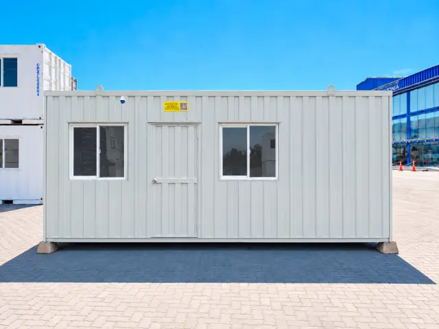 Frente completo del módulo: dos ventanas correderas con reja y la puerta de acceso entre ellas