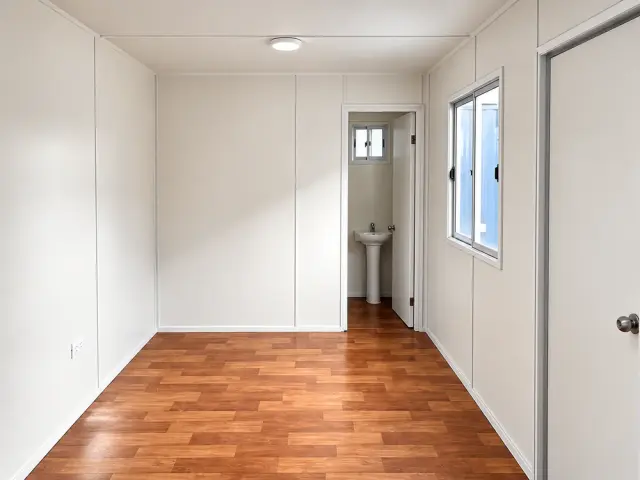 Interior con la puerta del baño abierta: el lavamanos y la ventanilla de ventilación al fondo del recinto