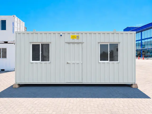 Frente completo del módulo: dos ventanas correderas con reja y la puerta de acceso entre ellas