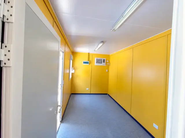 El mismo interior en planta libre mirando hacia la puerta de acceso, con la ventana y el equipo de aire al fondo