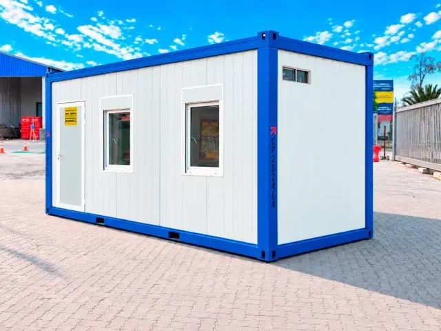 La misma oficina en tres cuartos desde el lado del acceso, con la puerta al centro y las ventanas a los costados