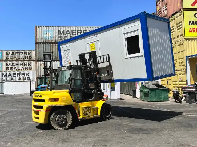 La oficina izada con grúa horquilla en el depósito, para mostrar que se traslada de una pieza